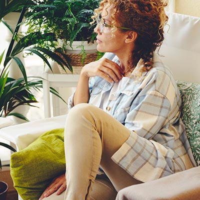 A woman sitting on a couch engaging in therapy while gazing at a plant.