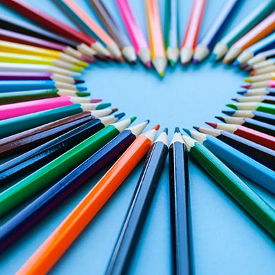 Colorful pencils arranged in a heart shape, offering art therapy for children and teens.