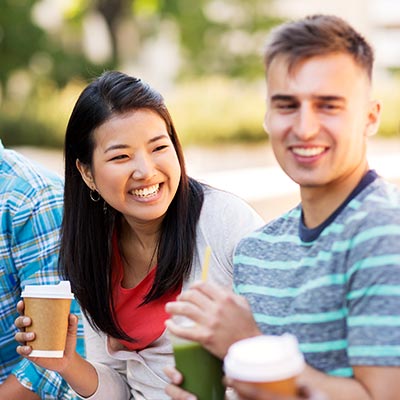 A group of young adults drinking coffee in a park.